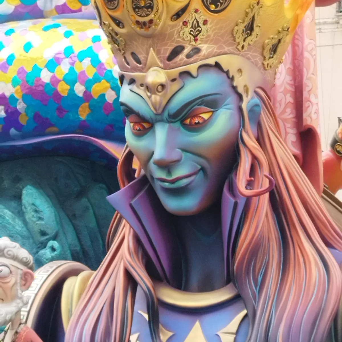 Close-up of a hand-painted ninot face with a jewelled crown showing the detailed craftsmanship of Las Fallas